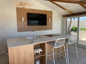 cocina con encimera, TV y 2 sillas en Lostane - Villa sur le toit, en Grimaud