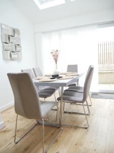 uma sala de jantar branca com uma mesa e cadeiras brancas em The Gill Penthouse, Ulverston - Lake District em Ulverston
