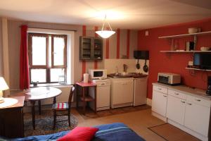une cuisine avec des murs rouges, des armoires blanches et une table dans l'établissement La Féculerie, à Harsault