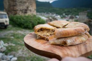 una persona che tiene un tagliere con un panino sopra di Gogi Jafaridze's Guesthouse a Mestia