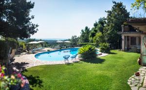 a swimming pool in a yard with chairs and trees at Villa Clodia Relais in Manziana