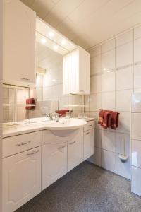 een witte badkamer met een wastafel en een spiegel bij Moselromantik-Hotel zum Löwen in Ediger-Eller