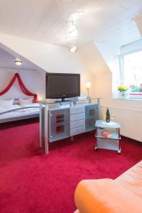 a living room with a tv and a red carpet at Moselromantik-Hotel zum Löwen in Ediger-Eller