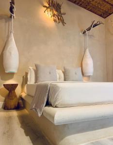 ein Schlafzimmer mit einem Bett mit zwei Vasen an der Wand in der Unterkunft Thari Fushi Luxury Maldivian Experience - All Inclusive in Thinadhoo