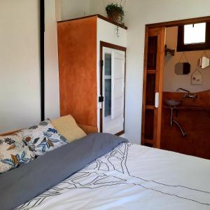 um quarto com uma cama e uma porta para uma casa de banho em Alpujarra Guesthouse, habitaciones en un cortijo sostenible y aislado en medio de la nada en parque natural Sierra Nevada a 1150 metros altitud em Cáñar