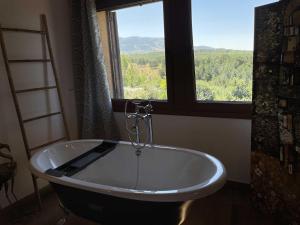bañera en una habitación con ventana en El Bulín de Montejo en Montejo de la Sierra