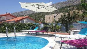 a swimming pool with chairs and an umbrella at Villa Blue View in Sumpetar
