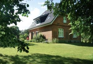 a brick house with a roof on a lawn at Gästehaus Kibbel in Bosau