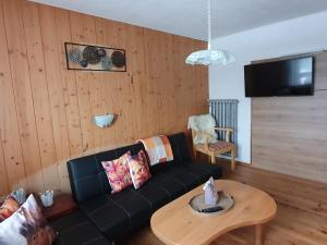 a living room with a black couch and a table at Bauernhof Neu-Endfelden, Günter Widauer in Söll