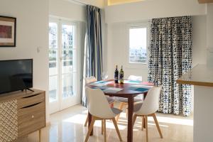 a dining room with a table and chairs and a television at CHROMA Lodge Rafina in Rafina