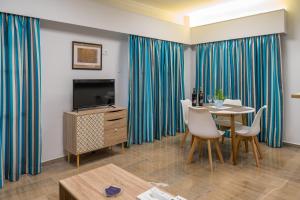 a living room with a dining table and a television at CHROMA Lodge Rafina in Rafina