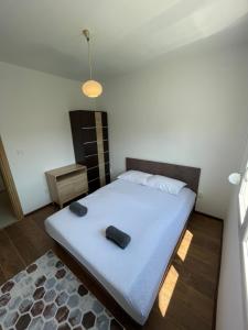 a bedroom with a large white bed with two black objects on it at Entire 1-bedroom apartment with free parking in Podgorica