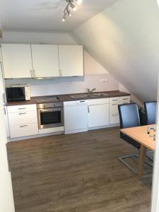 a kitchen with white cabinets and a table with chairs at Ferienwohnung auf dem Land in Wangerland