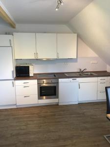 a kitchen with white cabinets and a sink and a microwave at Ferienwohnung auf dem Land in Wangerland