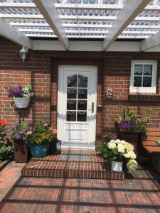 a front door of a brick house with pots of flowers at Ferienwohnung auf dem Land in Wangerland