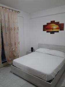 a white bed in a bedroom with a window at Casa vacanze Ginevra in Fondachello