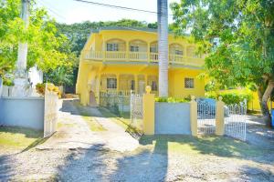 a yellow house with a gate in front of it at Unity Villa one bedroom apartment with, cable, park wifi,near beach in Montego Bay