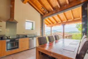 a kitchen with a wooden table and a large window at Pulieru - Picos de Europa views, designed for all seasons in Cangas de Onís