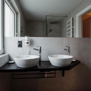 dwie białe umywalki na ladzie w łazience w obiekcie The Place Boutique & Design Hotel Flachau w mieście Flachau