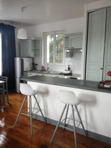 a kitchen with a white counter and two bar stools at Beaugency-2 sur la route des châteaux in Beaugency