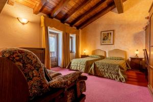 a hotel room with two beds and a chair at Hotel Des Alpes in Saint-Rhémy