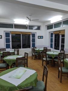 uma sala de jantar com mesas e cadeiras verdes em The Mother's Riverfront em Gushaini