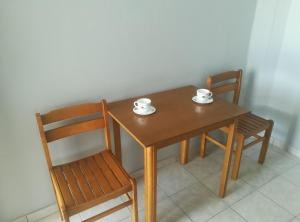 una mesa de madera con 2 sillas y 2 tazas. en Loginos Studios, en Kallithea Halkidikis