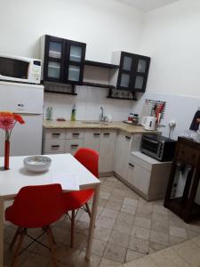 a kitchen with a white table and red chairs at Lovely apartment premium location in Ramat Gan