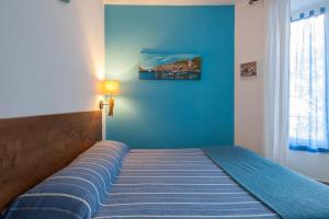 1 cama en un dormitorio con una pared azul en Sciuscettùa Rooms, en La Spezia