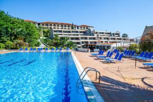 una piscina con sillas azules y un hotel en Xenios Theoxenia Hotel, en Ouranoupoli