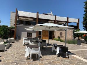 patio ze stołami, krzesłami i parasolami w obiekcie Tenuta Micoli w mieście Frisa