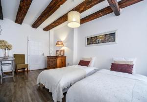 two beds in a bedroom with a table and a desk at Les Appartements De Louise in Riquewihr