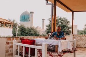 Hotel Dilshoda في سمرقند: رجل يجلس على طاولة في الفناء