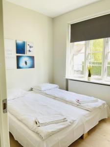 Duas camas num quarto branco com uma janela em aday - 2 bedroom apartment with Patio em Aalborg