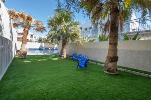 two blue chairs sitting on a lawn with palm trees at HI - Eilat Hostel in Eilat