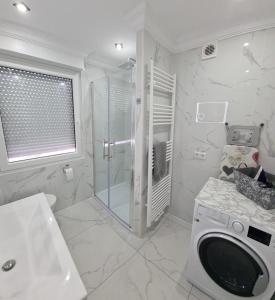 a white bathroom with a shower and a washing machine at R&S Apartments Bremen in Bremen +27 photos