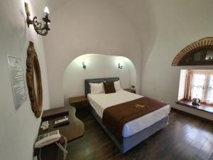 een slaapkamer met een bed, een telefoon en een raam bij Cesme Kanuni Kervansaray Historical Hotel in Çeşme