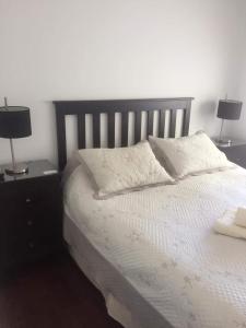 1 dormitorio con 1 cama con 2 lámparas en las mesas en AGUAMARINA en Puerto Madryn