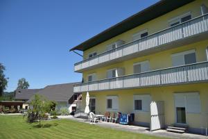 ein großes gelbes Gebäude mit Stühlen und Sonnenschirmen im Hof in der Unterkunft Ferienwohnungen Valerie in Sankt Primus am Turnersee