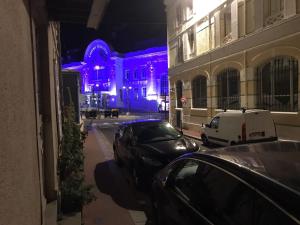 deux voitures garées devant un immeuble avec des lumières violettes dans l'établissement Trouville Plage Casino, à Trouville-sur-Mer