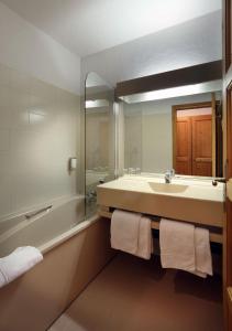 a bathroom with a sink and a tub and a mirror at Hotel Autantic in Bourg-Saint-Maurice
