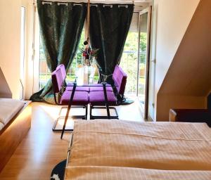 Cette chambre dispose d'une table avec des chaises violettes et d'une fenêtre. dans l'établissement Boutique Apartment Petite Belle, à Fribourg-en-Brisgau