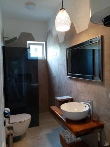 ein Bad mit einem Waschbecken und einem TV an der Wand in der Unterkunft Luxury apartment Tamaris by the sea in Nin