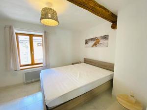 1 dormitorio con cama blanca y ventana en Résidence Saint-Jean, en Saint-Dalmas-le-Selvage