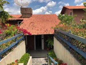 格雷夫森德的住宿－Casa Cantinho da Paz, seu lazer completo, churrasqueira, piscina e muita tranquilidade，一座红色屋顶的房子,还有一些鲜花