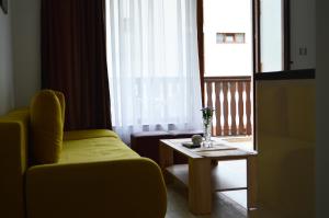 a living room with a yellow chair and a table at Aquamarine Apartments in Sveti Vlas