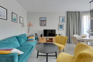 a living room with a blue couch and a table at Dom & House - Apartments Okrzei Prime in Sopot
