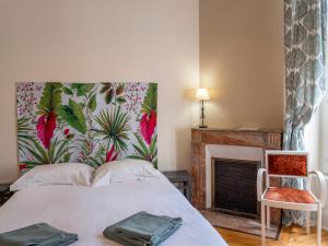 a bedroom with a bed with a floral headboard and a fireplace at La Villa François Premier in La Bourboule