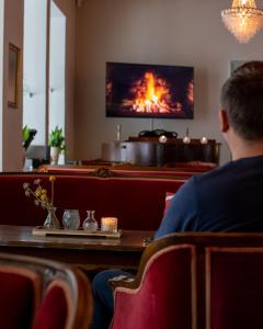 a man sitting at a table in a restaurant with a fireplace at Hotel Phønix Hjørring in Hjørring