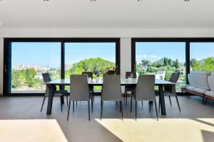 uma sala de jantar com mesa, cadeiras e janelas em SERRENDY - Custom villa with swimming pool em Mandelieu-la-Napoule